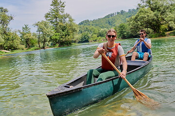 Image showing friends are canoeing in a wild river