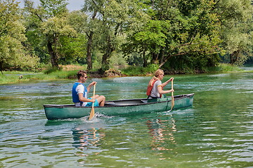 Image showing friends are canoeing in a wild river