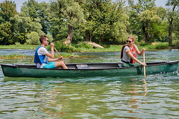 Image showing friends are canoeing in a wild river