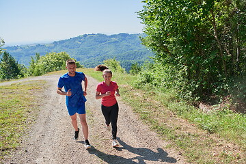 Image showing couple enjoying in a healthy lifestyle while jogging on a country road