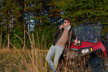 Image showing man smoking a cigarette while taking a break from driving a off road buggy car