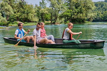 Image showing Group adventurous explorer friends are canoeing in a wild river