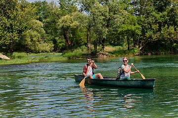 Image showing friends are canoeing in a wild river