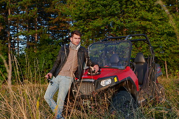 Image showing man smoking a cigarette while taking a break from driving a off road buggy car