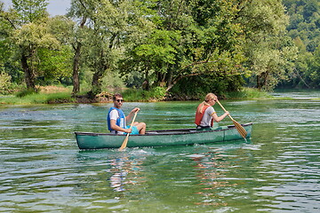 Image showing friends are canoeing in a wild river