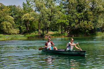 Image showing friends are canoeing in a wild river