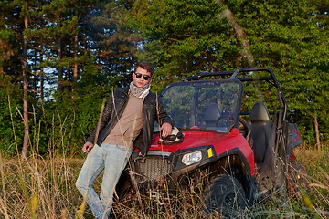 Image showing man smoking a cigarette while taking a break from driving a off road buggy car