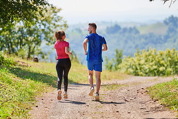 Image showing couple enjoying in a healthy lifestyle while jogging on a country road