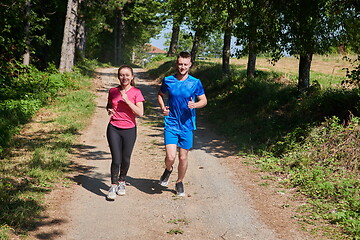 Image showing couple enjoying in a healthy lifestyle while jogging on a country road