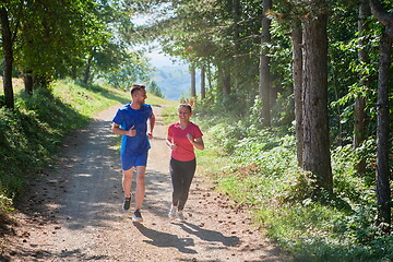 Image showing couple enjoying in a healthy lifestyle while jogging on a country road