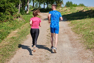 Image showing couple enjoying in a healthy lifestyle while jogging on a country road