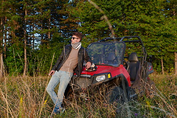 Image showing man smoking a cigarette while taking a break from driving a off road buggy car