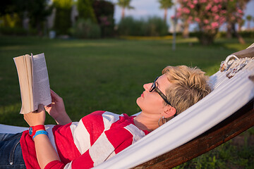 Image showing woman reading a book while relaxing on hammock