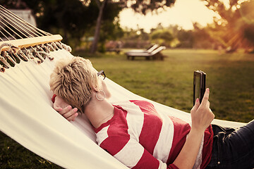 Image showing woman using a tablet computer while relaxing on hammock