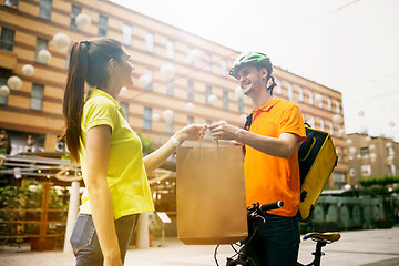 Image showing Young man as a courier delivering package using gadgets