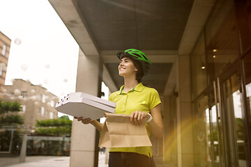 Image showing Young woman as a courier delivering pizza using gadgets