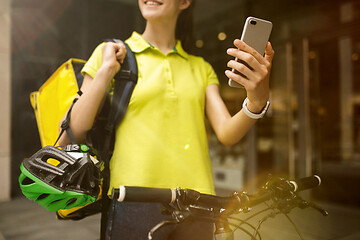 Image showing Young woman as a courier delivering food using gadgets