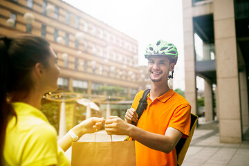 Image showing Young man as a courier delivering package using gadgets