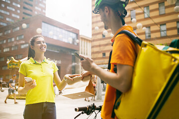 Image showing Young man as a courier delivering package using gadgets