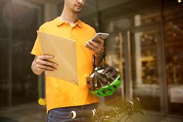 Image showing Young man as a courier delivering package using gadgets