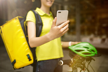 Image showing Young woman as a courier delivering food using gadgets