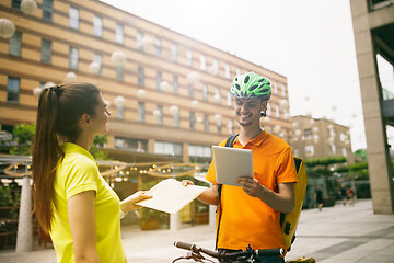 Image showing Young man as a courier delivering package using gadgets