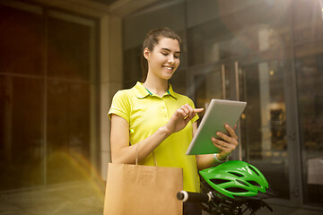 Image showing Young woman as a courier delivering package using gadgets