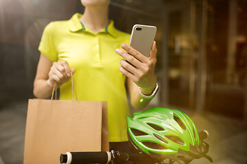 Image showing Young woman as a courier delivering package using gadgets