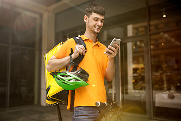 Image showing Young man as a courier delivering package using gadgets