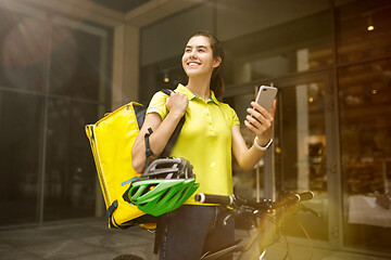 Image showing Young woman as a courier delivering food using gadgets