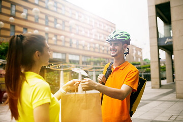 Image showing Young man as a courier delivering package using gadgets