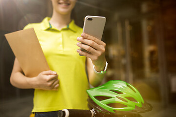 Image showing Young woman as a courier delivering package using gadgets