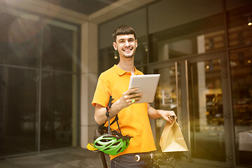 Image showing Young man as a courier delivering package using gadgets