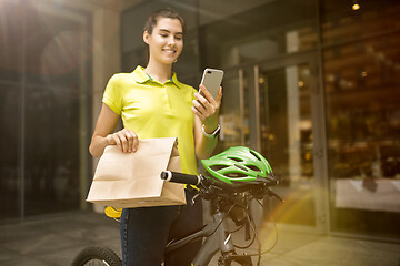 Image showing Young woman as a courier delivering package using gadgets