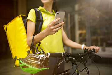 Image showing Young woman as a courier delivering food using gadgets