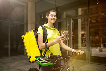 Image showing Young woman as a courier delivering food using gadgets