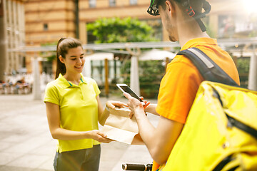 Image showing Young man as a courier delivering package using gadgets