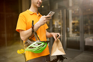 Image showing Young man as a courier delivering package using gadgets