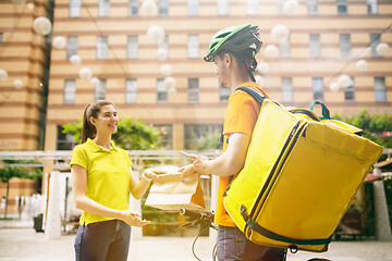 Image showing Young man as a courier delivering package using gadgets