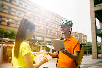 Image showing Young man as a courier delivering package using gadgets