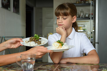 Image showing The girl thoughtfully chooses a dish for lunch