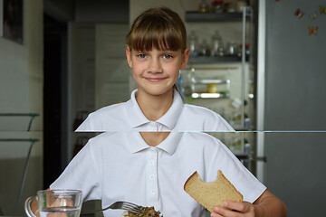 Image showing Portrait of a happy girl having dinner at the table in the kitchen