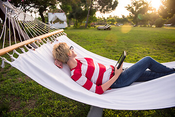 Image showing woman using a tablet computer while relaxing on hammock