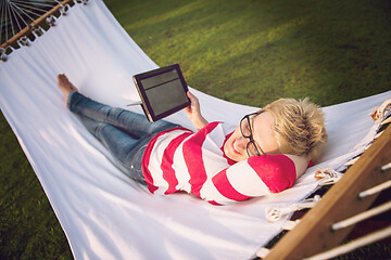 Image showing woman using a tablet computer while relaxing on hammock