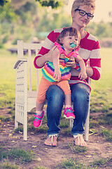 Image showing mother and cute little daughter sitting on wooden bench