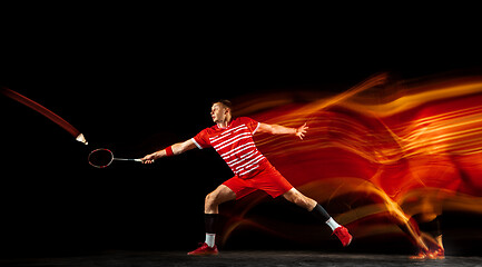 Image showing Young man playing badminton isolated on black studio background