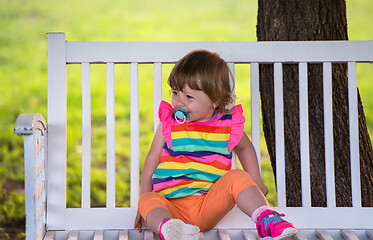 Image showing cute little girl sitting on wooden bench