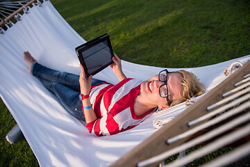 Image showing woman using a tablet computer while relaxing on hammock