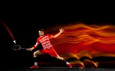 Image showing Young man playing badminton isolated on black studio background