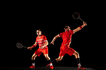 Image showing Young man playing badminton isolated on black studio background